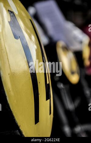 Rennzahlen auf klassischen Motorrädern, rennfertige Oldtimer-Motorräder, die beim historischen Goodwood Revival-Event in Großbritannien teilnehmen. In Fahrerlager-Garagen Stockfoto