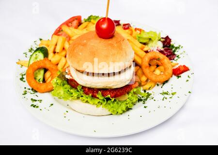 Hausgemachter Hamburger mit leckerem Rindfleisch auf weißem Teller, pommes Frites, Beilagen und Saucen Stockfoto