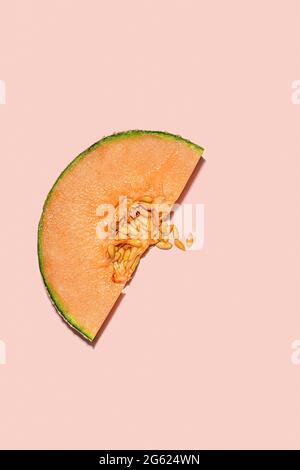 Glitzernde Scheibe aus Cantaloupe und Samen auf rosa nahtlosem Hintergrund. Der Hintergrund wird für eine einfarbige Farbe abgewischt, ideal für Grafikdesign. Stockfoto