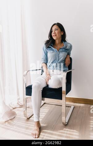 Elegante junge Frau, die eine Pause in ihrem Wohnzimmer Stockfoto