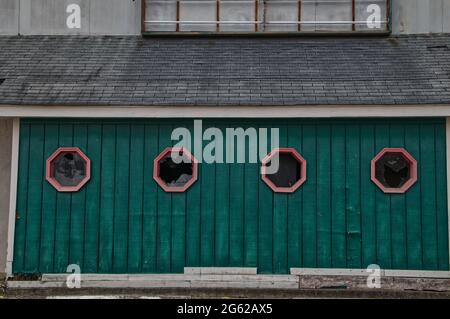 Alte Vintage strukturierte Holzwand mit verwitterten Fenstern und verwitterten Schindeln und kaputten Schildern Stockfoto