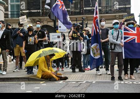 Ein Protestler in einem gelben Anzug hält während der Demonstration einen gelben Regenschirm vor der chinesischen Botschaft. Hongkongers veranstaltete Demonstrationen in zehn verschiedenen Städten in Großbritannien, um gegen den einjährigen Jahrestag der Promulgation des Hongkonger nationalen Sicherheitsgesetzes und den hundertjährigen Jahrestag der Kommunistischen Partei Chinas zu protestieren. In London versammelten sich die Teilnehmer vor der chinesischen Botschaft und marschierten nach Chinatown, wo die Hauptereignis stattfand. Die Massen zogen später zum Wirtschafts- und Handelsbüro von Hongkong und vergaßen rauchige Fackeln als symbolisches Zeichen der Verflucht der Hongkonger Bevölkerung Stockfoto