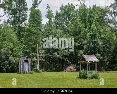 Altes hölzernes Nebengebäude neben einem überdachten Brunnen im ländlichen Alabama, USA. Stockfoto