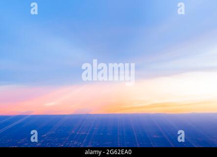 Abstrakter Sonnenuntergang über der Stadt- und Wüstenlandschaft bei Sonnenuntergang in Zoomunschärfe, aufgenommen vom Sandia Peak, Albuquerque, New Mexico, USA. Stockfoto