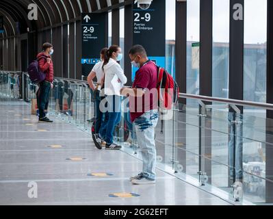 Medellin, Antioquia, Kolumbien - Mai 17 2021: Lateinischer Mann mit Maske und Blick auf sein Telefon in der Nähe der Fenster am Flughafen Stockfoto