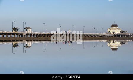 Melbourne Australien. Der historische St. Kilda Pier spiegelt sich in den stillen Gewässern der Port Phillip Bay wider. Stockfoto