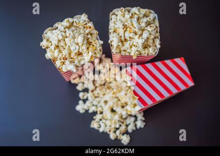 Popcorn in rot-weißem Behälter auf dunklem Hintergrund Stockfoto