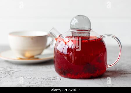 Beerentee in Glas Teekannen auf grauer Oberfläche Stockfoto