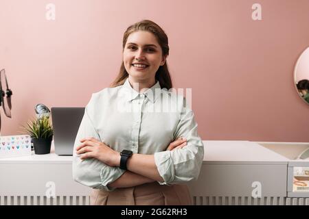 Porträt eines jungen Boutique-Besitzers, der an der Theke steht. Lächelnde Frau in ihrem Bekleidungsgeschäft. Stockfoto