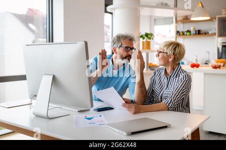 Glückliche reife Kollegen im modernen Büro mit Computer und Brainstorming. Stockfoto