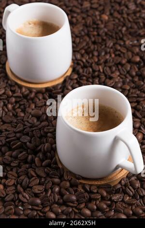 Zwei Tassen Kaffee auf dem Hintergrund der Kaffeebohnen. Nahaufnahme Stockfoto
