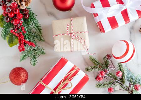 Weihnachtliche Kulisse aus Tannenzweigen, roten Beeren, Geschenkschachteln und Kugeln auf Marmorhintergrund. Weihnachten Hintergrund. Flach liegend, Draufsicht. Stockfoto
