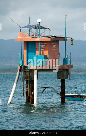 Frühwarnsystem-Station mitten im Meer mit Bergen im Hintergrund. Tsunami, Hochwasser- und Niedrigwassererkennung zur Vorbeugung und Sicherheit. Stockfoto