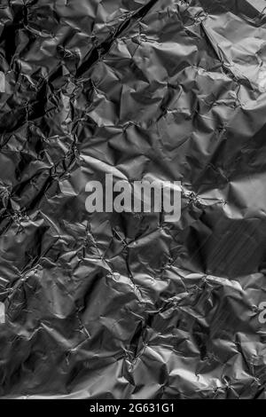 Zerknitterte, zerknitterte Aluminiumfolie aus Metall. Grunge abstrakten detaillierten dunkelgrauen Hintergrund Stockfoto