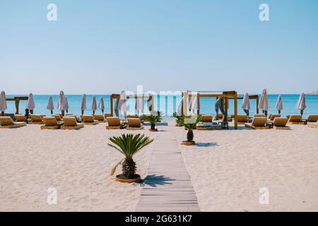 Paralia Platis Gialos Beach Mykonos, Petinos Beach Mikonos Island Griechenland, luxuriöse Strandliegen und blaues Meer. Mykonos Griechenland April 2018 Stockfoto