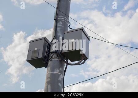 Elektrischer Transformator auf einem Mast. Elektrische Anlagen in Kästen. Ein Mittel zur Stromversorgung. Säule mit Kommunikation. Stockfoto