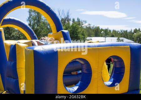 Aufblasbarer Hindernisparcours für Spaß. Aufblasbare Struktur im Park. Ein Ort für die Freude der Kinder. Spielplatz. Butut ist gelb-blau. Stockfoto