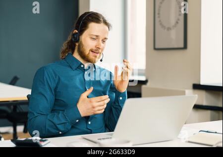 Junger Mann, professioneller Callcenter-Mitarbeiter, der mit dem Kunden im Gespräch ist Stockfoto