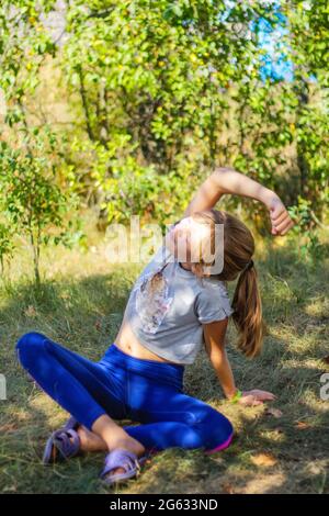 Defocus caucasian preteen Mädchen praktiziert Yoga im Park, Wald, im Freien, draußen. Meditation, Konzentration. Gesunder Lebensstil. Portrait von Yoga Mädchen. Stockfoto