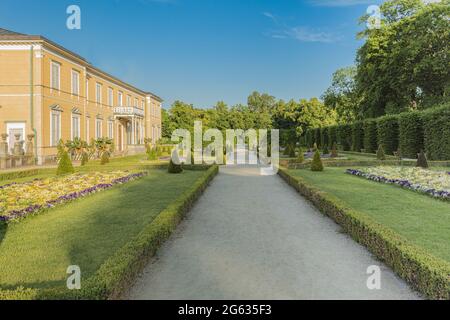 Eine schöne Landschaft eines Stadtparks mit Pfaden, Blumenbeeten und Bäumen. Schöne Natur in einem ruhigen grünen Park. Gut gepflegter Park Stockfoto