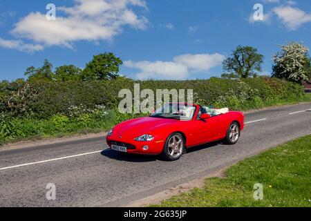 2002 rotes Jaguar XK8 4196 ccm Benzin-Cabrio, 2dr Zweisitzer auf dem Weg zur Capesthorne Hall Classic Car Show im Mai, Cheshire, Großbritannien Stockfoto