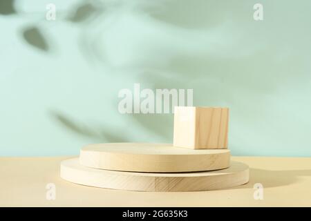 Minimale moderne Komposition mit Holzständer für Kosmetikprodukte mit Schattenüberzug auf neutralem Blau und Beige Hintergrund. Stockfoto