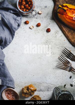 Food Frame Hintergrund mit saisonalen Herbstprodukten.gerösteter Kürbissalat, Grünkohl, Brot, Nüsse und Samen. Stockfoto