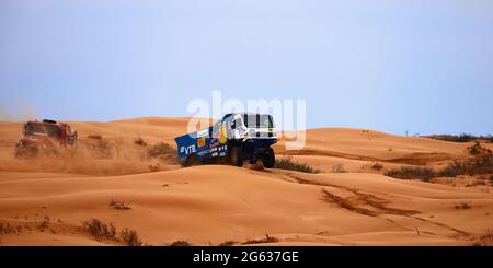 Die Rivalität zwischen Kamaz und Maz bei der Rallye. Der Sporttruck KAMAZ übersteht den schwierigen Teil der Strecke während des Rallye-Angriffs im Sand. DAS GOLD Stockfoto