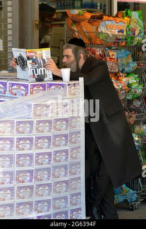 Ein orthodoxer Jude liest AMI (Hebräisch für mein Land), eine Zeitschrift für orthodoxe Juden, mit einer Titelgeschichte über Donald Trump. In Brooklyn, New York. Stockfoto