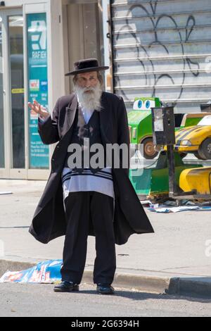 Ein orthodoxer jüdischer Mann deutet auf einen Bus auf der Lee Avenue in Williamsburg, Brooklyn, New York City. Stockfoto