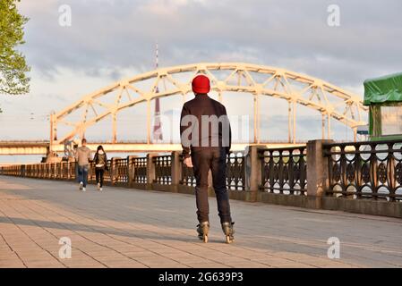 Ein junger Mann, der in der Stadt Schlittschuh läuft, kommt schnell an sein Ziel. Der Einsatz von Rollschullen in der Stadt als eine Form des städtischen Verkehrs. Stockfoto