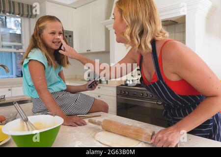 Glückliche kaukasische Mutter und Tochter, die Spaß beim Backen in der Küche haben Stockfoto