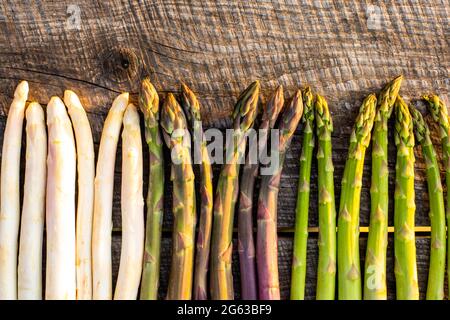 Weißer, violetter und grüner Spargel auf Holztisch Stockfoto