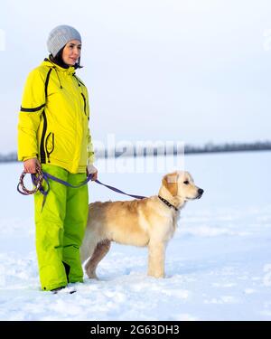 Glückliche Frau mit schönen Hund zu Fuß im Winter Stockfoto