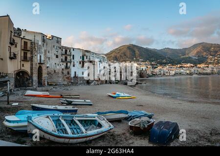 Schöner alter Hafen mit hölzernen Fischerbooten, farbenfrohen Steinhäusern am Wasser und Sandstrand in Cefalu, Sizilien, Italien.Attraktive sommerliche Stadtlandschaft Stockfoto