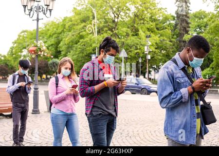 Menschen in Masken stehen Schlange, um soziale Distanz zu bewahren Stockfoto