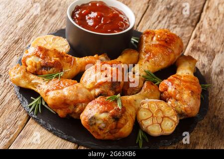 Rustikale Stil köstliche gegrillte Hähnchendrumsticks mit Knoblauch und Rosmarin mit bbq-Sauce close-up auf einem Schieferbrett auf dem Tisch. Horizontal Stockfoto