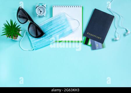 Reisepass und medizinische Maske auf blauem Hintergrund. Sicheres Reisekonzept während der Coronavirus-Pandemie. Flatlay, Kopierbereich. Stockfoto