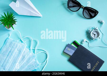 Sicheres Reisekonzept während der Coronavirus-Pandemie. Reisepass, medizinische Maske und Sonnenbrille auf blauem Hintergrund. Flatlay, Bannerformat. Stockfoto