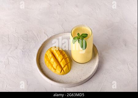 Lassi Drink ist Smoothies oder Milchshake auf hellem Hintergrund. Traditionelles indisches und pakistanisches Getränk mit Joghurt, Mango, Gewürzen, Minze und Eis Stockfoto