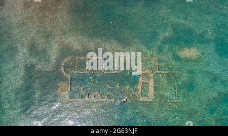 Alte versunkene Stadt Epidaurus bei Argolida, Griechenland Luftaufnahme, Drohne von oben nach unten. Griechisches Atlantis unter Wasser mit gut erhaltenen Ruinen, Wellenbrecher. Swi Stockfoto