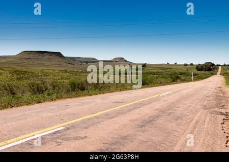 Eine Straße ohne Autos und einige Hügel im Hintergrund in Uruguay, neben Tacuarembó. Klassische Hügelformationen in diesem Teil des Landes. Stockfoto