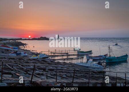 Ahtopol - 10. September: Sonnenaufgang am Strand mit Fischerpier, Felsen und Leuchtturm am 10. September 2016, Ahtopol, Bulgarien Stockfoto