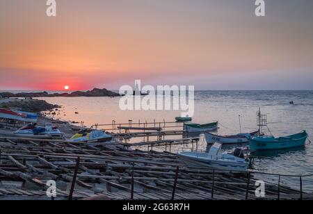 Ahtopol - 10. September: Sonnenaufgang am Strand mit Fischerpier, Felsen und Leuchtturm am 10. September 2016, Ahtopol, Bulgarien Stockfoto