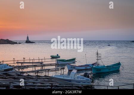 Ahtopol - 10. September: Sonnenaufgang am Strand mit Fischerpier, Felsen und Leuchtturm am 10. September 2016, Ahtopol, Bulgarien Stockfoto