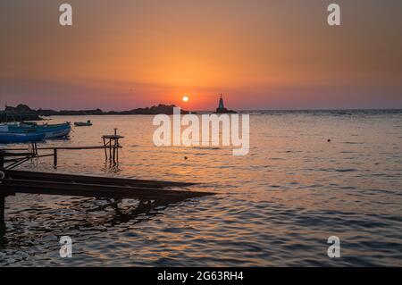 Ahtopol - 10. September: Sonnenaufgang am Strand mit Fischerpier, Felsen und Leuchtturm am 10. September 2016, Ahtopol, Bulgarien Stockfoto