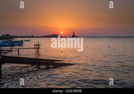 Ahtopol - 10. September: Sonnenaufgang am Strand mit Fischerpier, Felsen und Leuchtturm am 10. September 2016, Ahtopol, Bulgarien Stockfoto