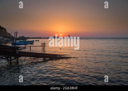 Ahtopol - 10. September: Sonnenaufgang am Strand mit Fischerpier, Felsen und Leuchtturm am 10. September 2016, Ahtopol, Bulgarien Stockfoto