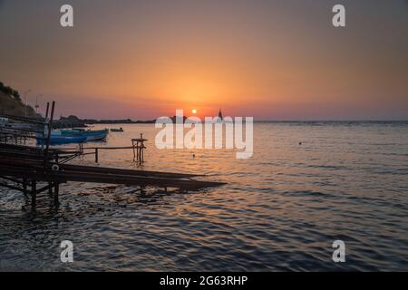 Ahtopol - 10. September: Sonnenaufgang am Strand mit Fischerpier, Felsen und Leuchtturm am 10. September 2016, Ahtopol, Bulgarien Stockfoto