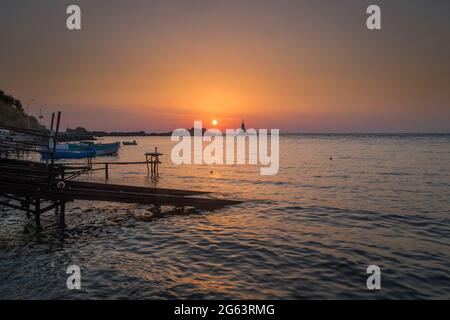 Ahtopol - 10. September: Sonnenaufgang am Strand mit Fischerpier, Felsen und Leuchtturm am 10. September 2016, Ahtopol, Bulgarien Stockfoto